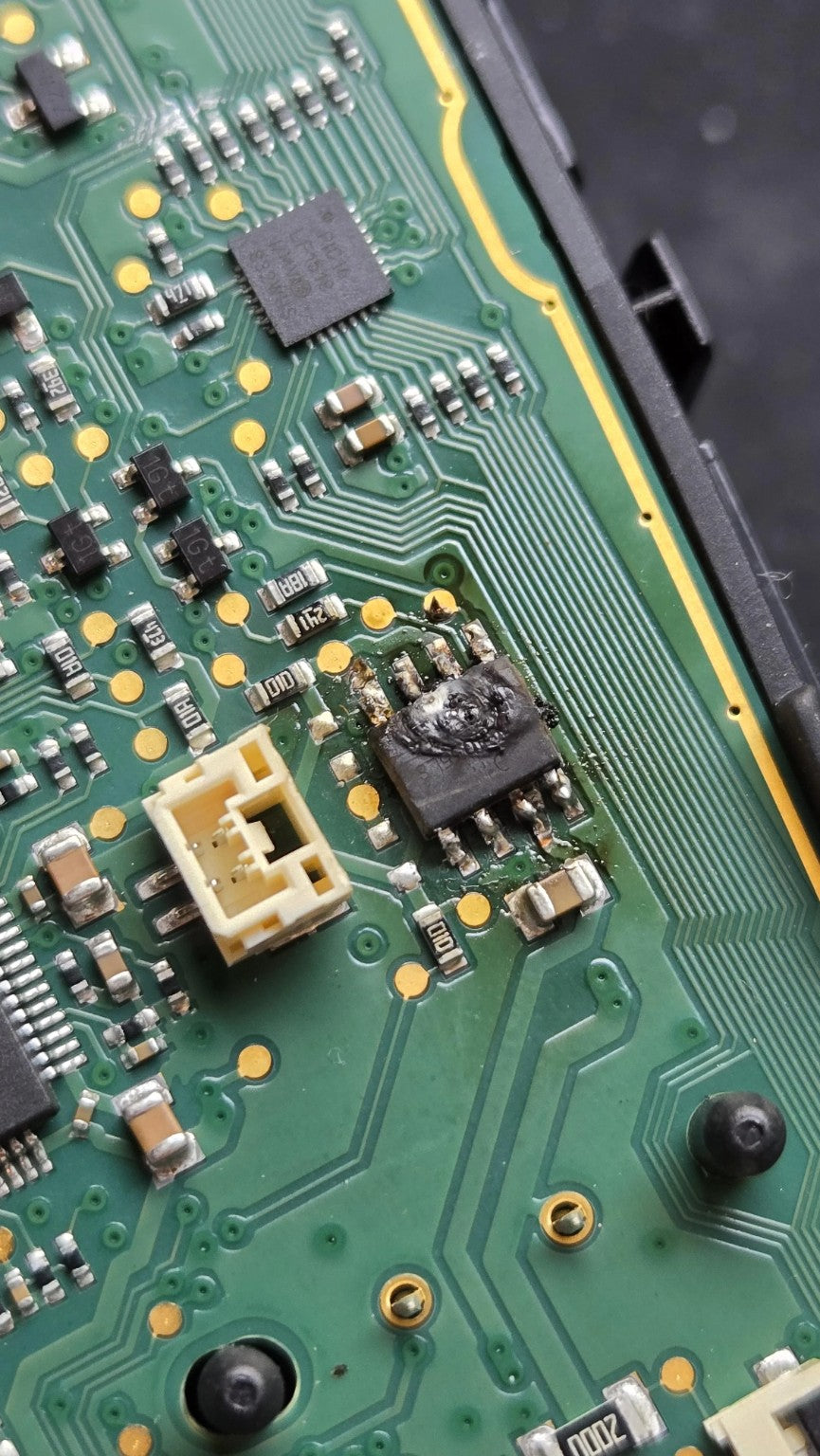 Original damage reference photograph showing the cratered eight-pin chip beside the cream-coloured connector. PCB and console are not included.